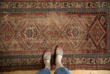 Central field of an antique Kurdish rug, showing diamond medallions, animal motifs, and historic wear.
