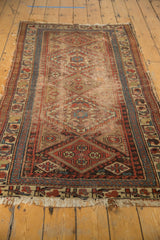 Aged patina on an antique Kurdish rug, revealing muted geometric patterns and soft colors.