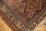 Antique Kurdish rug corner shows madder red, sky blue hook and latch border with visible wear.