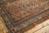 Antique Kurdish rug corner with geometric diamond motifs, hook and latch border, and visible wear.