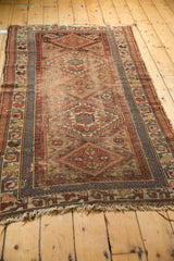 Antique Kurdish rug with diamond medallions, serpent figures, hook border, and storied wear.