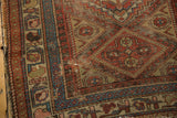 Antique Kurdish rug detail: geometric hook border, madder red field, and noticeable pile wear.