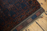 Antique Belouch rug's deep indigo and burgundy geometric patterns, with plain woven end.
