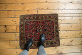 Vintage American Sarouk rug corner with cherry red floral field, secured side, and tattered fringe.