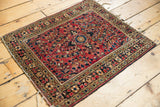 Vintage American Sarouk rug corner: cherry red field with navy and ivory floral border.