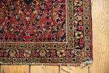 Vintage American Sarouk rug corner with cherry red field, floral motifs, and tattered fringe.