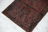 Antique Mohajeran Sarouk rug edge showing light loss, small split, and faded plum floral motifs.