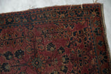 Antique Mohajeran Sarouk rug edge showing plum, navy floral design, mostly even wear, and faint foundation.