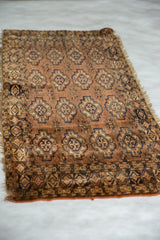 Antique Turkmen mat runner's repeating floral guls, geometric border, and tattered lower edge.