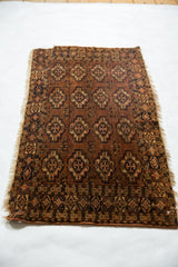 Turkmen rug's tattered lower end, detailing geometric border and chestnut floral guls.