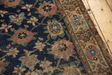 Antique Kurd rug's tattered edge, geometric border, and worn navy field with Veramin motifs.