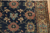 Detail of antique Kurd rug: navy ground with madder red motifs, worn geometric border, tattered edge.