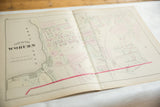 Angled view of an open 1875 Woburn, MA atlas map showing the center crease and landowners' plots.