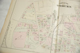 Angled close-up of the antique Woburn atlas showing landowners' names and property lines.