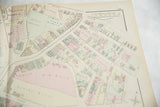Angled detail of an antique Woburn, MA map showing color-coded plots and landowner names.
