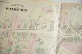 Angled detail of an 1875 Woburn atlas map showing Town Hall, churches, and property lines.