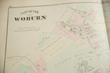 Angled view of the title and hand-colored property plots on an antique Woburn map.