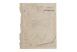 An antique 1875 map of Woburn, Massachusetts, showing property plots and street grids on aged paper with a tattered binding.