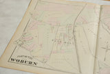Angled view of the antique Woburn, Massachusetts map showing landowner names and property lines.
