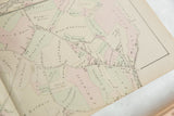 Angled close-up of an antique Woburn map showing landowners' names and colored property lines.