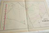Angled view of the antique 1875 Woburn atlas map, showing its central fold and aged paper.