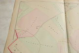 Angled detail of an antique Woburn map showing landowners names on pastel-colored properties.