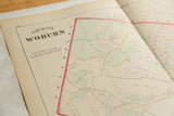 Title block and landowner parcels with pastel coloring on an antique Woburn atlas map.