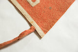 Staining on the sewn ivory border and orange tie of an antique felt pennant.