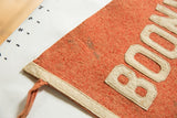 Close-up showing staining and texture on the orange wool felt of the antique pennant.