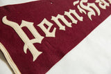 Stitched white felt letters in a gothic style on the maroon wool pennant.