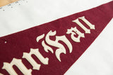 Detail of the antique pennant's maroon wool texture, sewn lettering, and visible pin holes.