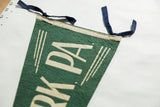 The creased wool texture, cream binding, and blue felt ties of a vintage pennant.