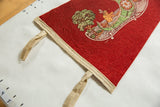 Red felt texture on the Utica pennant's corner, featuring cream binding and canoe illustration.