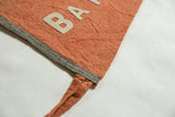 Close-up of antique Batavia felt pennant with orange wool, grey binding, and white 'BA' letters.