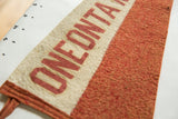 Fibrous texture of the orange wool felt and stitching on the vintage pennant.