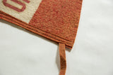 Double-stitched hem and attached tie on the textured orange felt of an antique pennant.