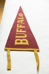 Vintage maroon felt Buffalo pennant with bold yellow lettering and aged texture.