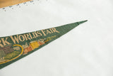 Green felt tip of vintage World's Fair pennant, with architectural imagery and creased texture.