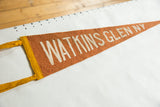 Visible 'Watkins Glen NY' lettering on russet felt antique souvenir pennant with yellow binding.
