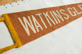 Antique felt pennant with textured orange felt, cream 'WATKINS GL' text, yellow trim.