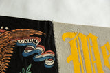 Close-up of the vintage West Point felt pennant's zig-zag seam joining black 'UNUM' section to gray 'M'.