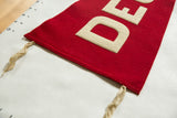 Antique red wool felt pennant corner, with creamy 'D' applique and tie.
