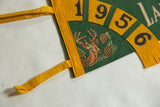 Fringed tip of the green and gold vintage felt pennant with dark blue number six.