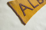 Goldenrod felt pennant tip shows oxidized purple letter detail and pinhole.
