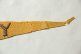Goldenrod yellow felt pennant, faded purple Y, showing worn texture and tip loss.
