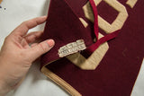 Vintage maroon felt pennant, showing original fabric label and wool texture.