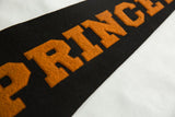 Stitched orange block letters on the black felt Princeton University pennant.