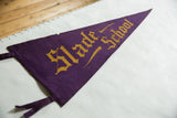 Angled view of the antique Slade School pennant in deep purple felt with gold Gothic lettering.