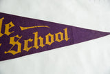 Pointed tip of the antique purple felt pennant with worn yellow gothic lettering.