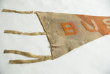 Worn beige felt texture of the antique pennant with orange B and frayed ties.